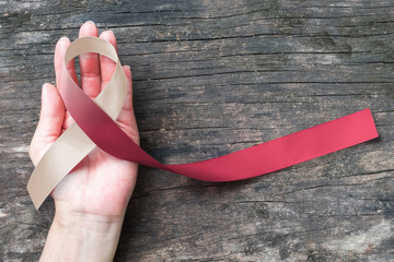 Head and neck cancer symbolic burgundy ivory white color ribbon isolated on human hand (clipping...
