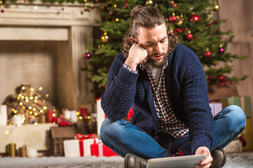 Thoughtful man using digital tablet