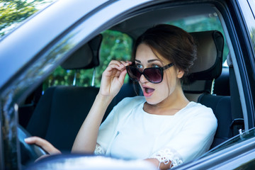 Fototapeta na wymiar surprised girl in sunglasses driving a car