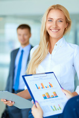 Portrait of young businesswoman in office with colleagues in the background