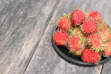 rambutan sweet fruit fresh in plate on wood background :Select focus with shallow depth of field.