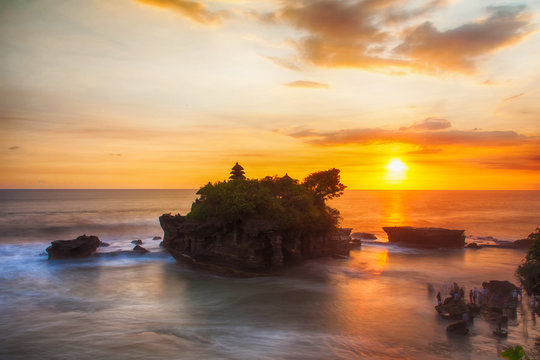 Sunset at Bali's famous Tanah Lot temple, Indonesia. People and waves  in motion blur.
