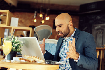 Modern man working on a laptop and has a problem in a cafe