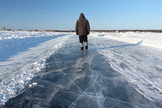 Man walking along a road of ice on the frozen reservoir in the winter, Ob River, Siberia, Russia