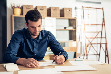 Focused businessman writing on paperwork in a studio