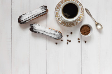 Chocolate eclairs and coffee on a wooden background