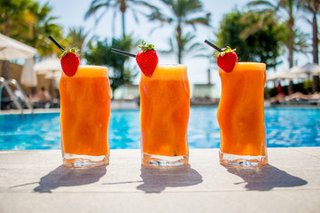 Zumo de naranja con fresa en la piscina
