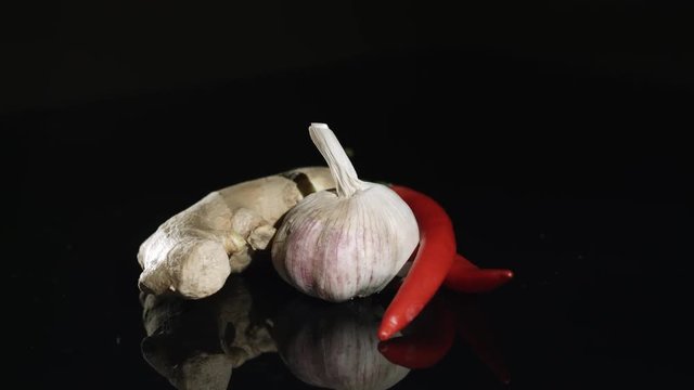 Spices ginger garlic and chili pepper rotating on reflective surface