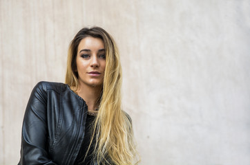 Fototapeta premium Portrait of attractive blonde young woman in black leather jacket, outdoor looking at camera