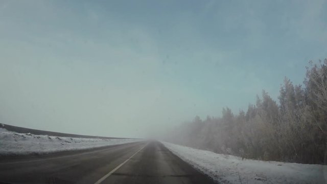 Driving car in winter. The sun shines through the fog