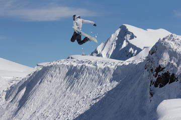 Naklejka na ściany i meble Jumping snowboarder in winter mountain. Extreme sport.