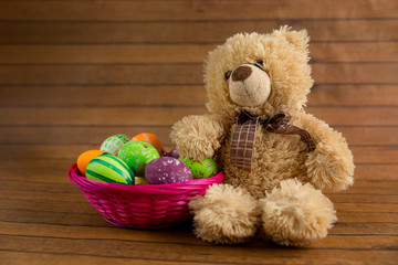 Easter color painted eggs in basket and teddy bear