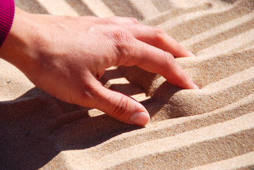MANO DE UNA MUJER TOCANDO LA ARENA DE LA PLAYA © MIKYIMAGENARTE