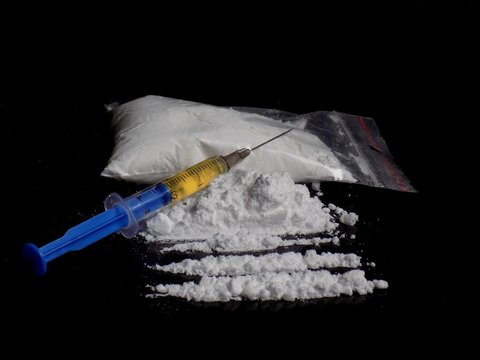 Injection syringe on cocaine drug powder bag, pile and lines