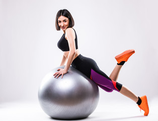 Portrait of young attractive woman doing exercises. Brunette with fit body holding fitness ball.