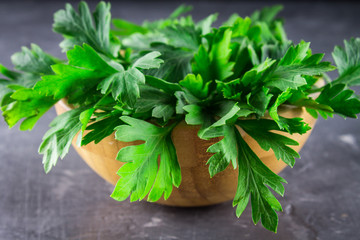 parsley in a wooden bowl on a gray background