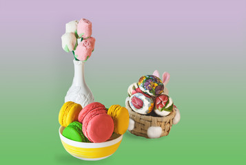 Easter colorful sweet macaroon marshmallow flowers in a white vase, colorful eggs in a basket on a Colored background