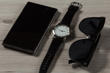 Watch, sell phone, sunglasses on a gray wooden background