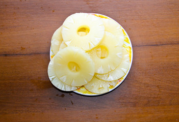 Canned pineapple on a plate on wooden table