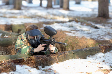 girl playing paintball in overalls with a gun.