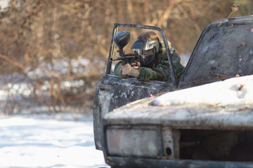 girl playing paintball in overalls with a gun.