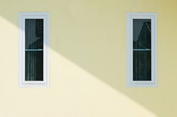 wall yellow house with two windows.