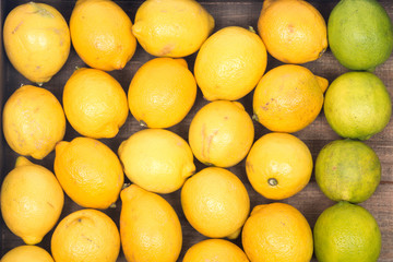 Ripe organic limes and lemons in wooden vintage tray like background