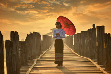 The beautiful woman Myanmar in U-bein bridge on during sunrise, treaditional culture...