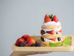Beautiful women hold a mix berry cake in hand close up