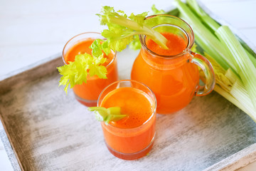 Fresh carrot juice poured into glasses and green celery