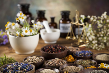 Alternative medicine, dried herbs and mortar on wooden desk background