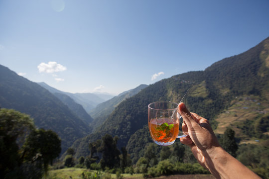 Travelling Female hand holding a cup of mint tea with mountain view