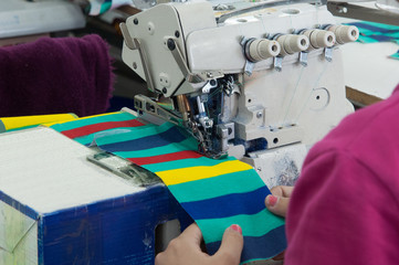 closeup seamstress on the machine sews clothes at a garment factory
