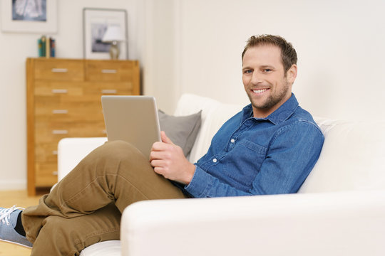 glücklicher mann mit laptop auf dem sofa