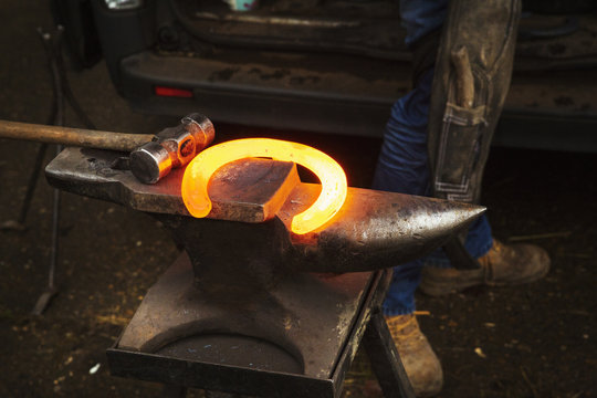 A hammer and anvil, and a red glowing heated metal horseshoe.