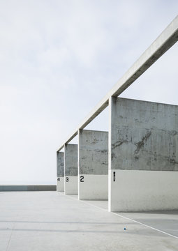 Numbered concrete pillars in handball court against blue sky