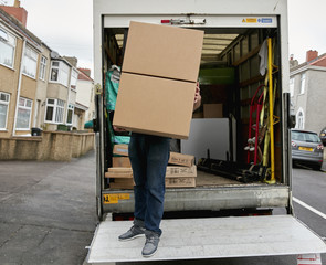 Removals business. A man on the tailgate of a van carrying a large box. 