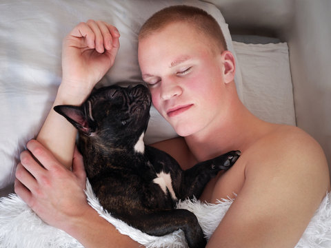 Young Man And Dog Sleeping Together On The Bed