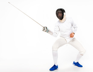 Man wearing fencing suit practicing with sword against gray