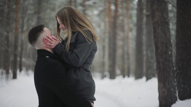 20s Man is lifting his girlfriend and having a fun in a snow winter forest