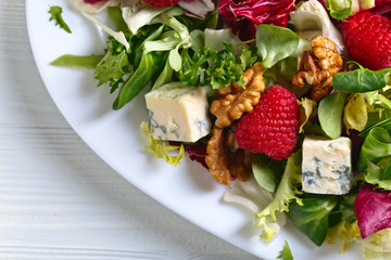 Green spring salad with blue cheese , raspberry and nuts