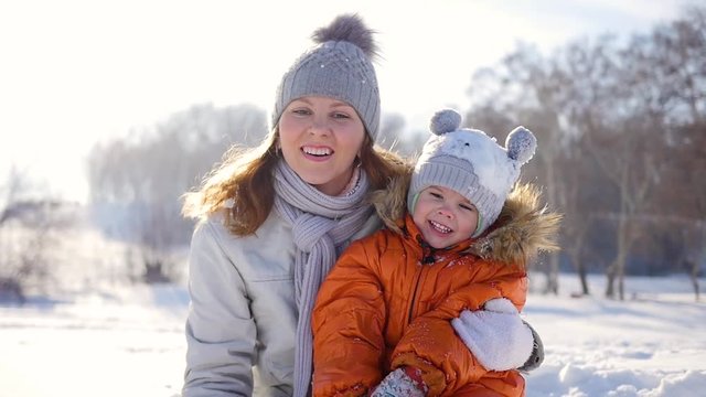 Girl plays with baby at sunny in winter time. Holding on hands