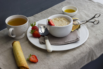 Oatmeal with fresh strawberries on linen fabric. Wafer with a boiled condensed milk and honey for...