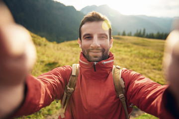 Man in hiking gear taking a selfie outside