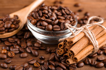 Coffee beans and cinnamon on a background of burlap. Roasted coffee beans background close up. Coffee beans pile from top with copy space for text. Seasoning. Spice. Cinnamon. Badian. Coffee house.