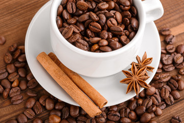 Coffee beans and cinnamon on a background of burlap. Roasted coffee beans background close up. Coffee beans pile from top with copy space for text. Seasoning. Spice. Cinnamon. Badian. Coffee house.