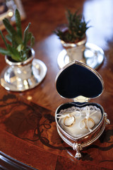 Fedi nuziali dentro cofanetto a forma dicuore d'argento sopra tavolo in legno antico