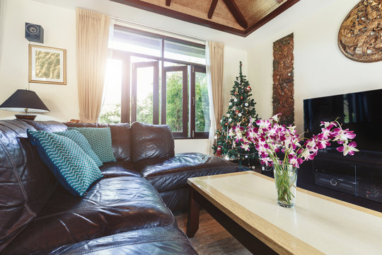 living room interior in luxury villa: sofa, tv, open window, tropical orchid flowers, summer