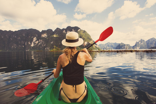 Beautiful female wearing hat traveling by boat in mountain tropical lake. Summer Travel concept, Thailand, Cheow lan lake