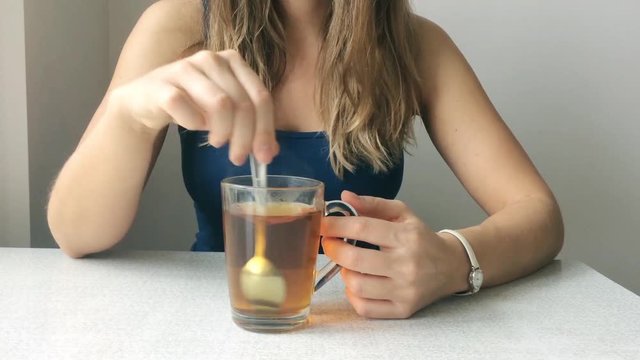 Portrait of a beautiful young woman with blonde hair prevents spoon tea